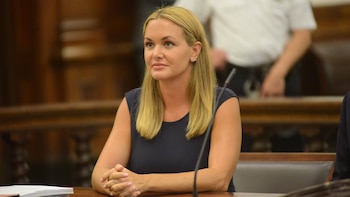 Primer plano de Vanessa Trump, una mujer rubia de mediana edad con blusa azul marino, sentada en una mesa de madera con las manos entrelazadas