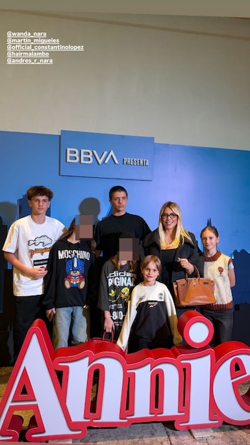 Wanda Nara, de gafas, posa con sus cinco hijos de diferentes edades frente a un gran cartel rojo y blanco con 'Annie' y un logo de 'BBVA PRESENTA' azul