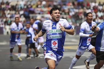 Jugador de Collaval con camiseta azul y blanca, celebrando con expresión de alegría. Otros jugadores y público borroso se ven de fondo en un día soleado