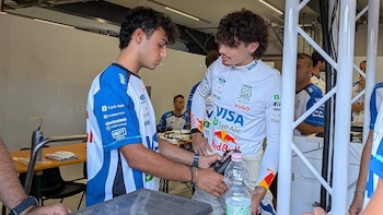 Nikola Tsolov con traje blanco de piloto habla con un integrante del equipo junto a una mesa con herramientas dentro de un garaje
