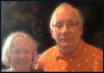 Un primer plano muestra a un hombre y una mujer mayores; él con gafas y una camisa naranja de lunares, ella con cabello rubio claro y una sonrisa