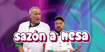 Dos hombres, Shiky y Arath de la Torre, vestidos con chaquetas de chef, posan sonrientes frente a un fondo abstracto colorido con el texto "Sazón a mesa"