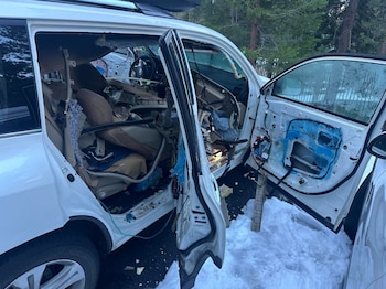 Interior destrozado de un SUV blanco con asientos y paneles de puertas arrancados, mostrando cables expuestos y escombros. Nieve visible en el suelo