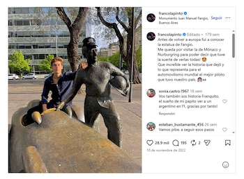 Franco Colapinto, un joven, posa con una camisa azul junto a una estatua de bronce de Juan Manuel Fangio que sostiene un casco, y una réplica de coche de carreras