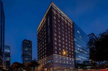 Vista exterior de la torre Casa Andina Premium San Isidro de noche, con su fachada oscura y ventanas iluminadas, junto a otro rascacielos de cristal