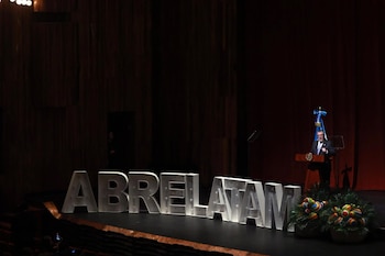 Personas sobre un escenario frente a un telón rojo junto a la palabra ABRELATAM en letras grandes, una bandera guatemalteca y fotógrafos