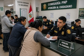 Agentes policiales atienden a personas tras un mostrador en una oficina con un letrero de atención al ciudadano y una bandera peruana