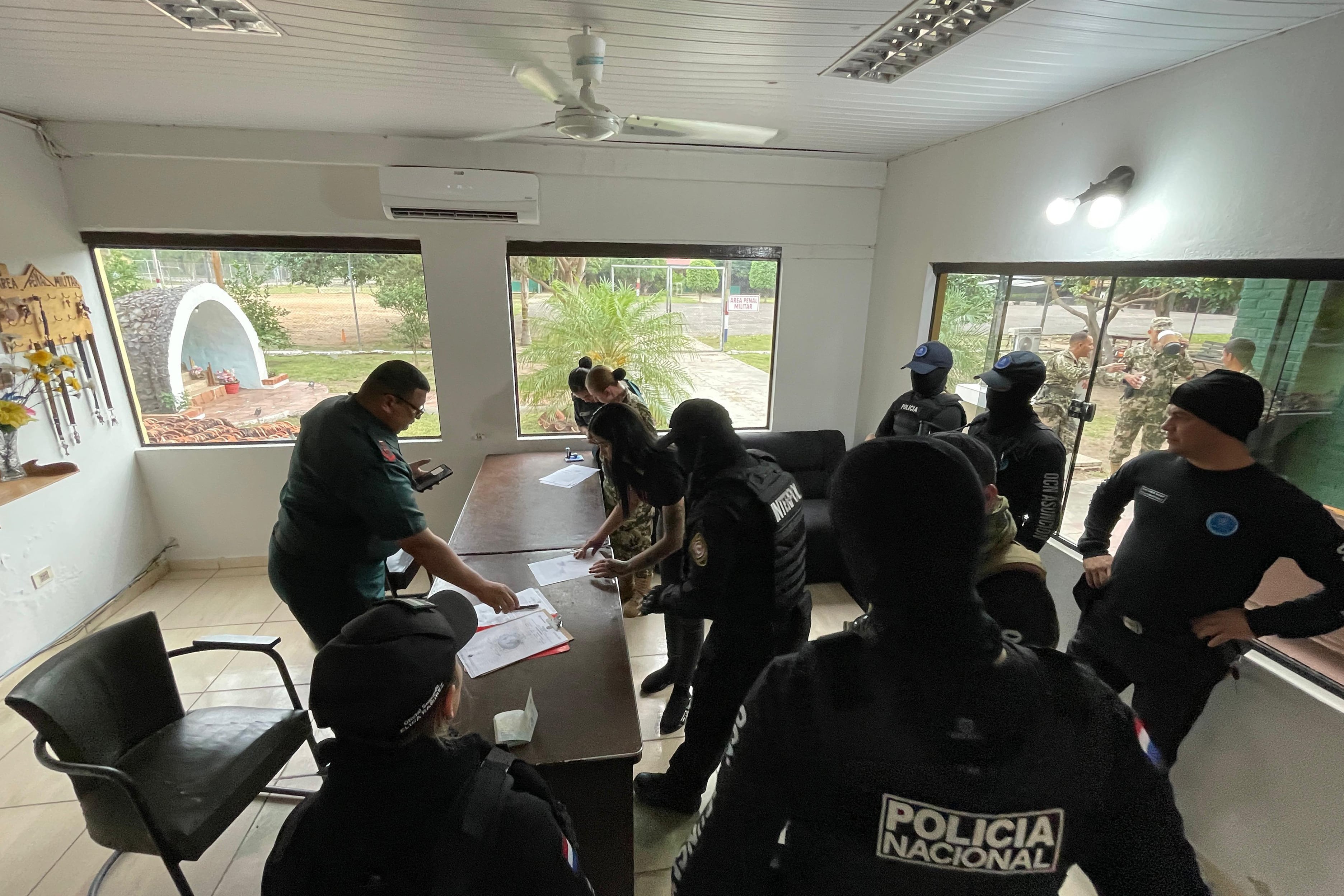 La esposa del presunto narcotraficante uruguayo Sebastián Marset, Gianina García Troche (c, atrás), durante su reseña por agentes de Interpol (EFE/ Interpol Paraguay)