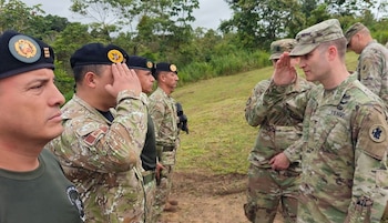 Soldados de Perú con boinas negras y militares de EE UU con uniforme de camuflaje multicam se saludan formalmente al aire libre, con un fondo de vegetación densa