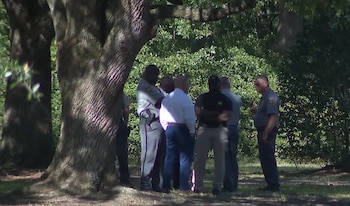 Un grupo de agentes de policía de pie bajo la sombra de unos grandes árboles en un área verde