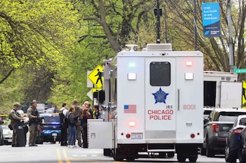 Vehículo táctico blanco de la policía de Chicago con luces encendidas en calle urbana. Agentes y personal con equipo táctico. Árboles y banner de Endeavor Health