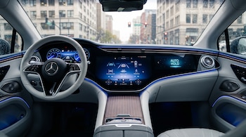 Interior de cabina de automóvil de lujo con volante blanco, tablero digital, pantalla multimedia con sistemas de asistencia y vista urbana exterior a través del parabrisas mojado.