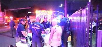 Bomberos de Miami atienden a varias personas en la calle frente a una ambulancia con luces de emergencia encendidas