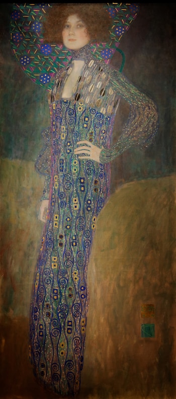 Pintura al óleo de cuerpo entero de Emilie Flöge, vestida con un traje ornamental de patrones azules, dorados y verdes, con el cabello castaño rojizo