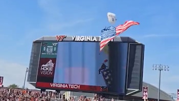 Impactante golpe de un paracaidista contra la pantalla gigante del estadio Lane durante la ceremonia previa al partido de fútbol americano en Virginia Tech