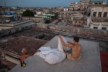 Alexis Milan y su hijo de 17 años suben cada noche a la azotea de su edificio en La Habana para intentar descansar. (YAMIL LAGE / AFP)