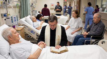 Un sacerdote con sotana negra y estola blanca ora sobre un paciente en cama. Se observa una Biblia abierta, otros pacientes, familiares y equipo hospitalario.