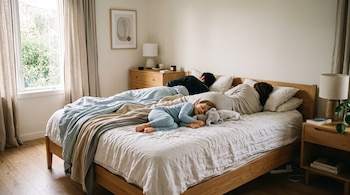 Un hombre, una mujer y un niño pequeño con pijama de color azul duermen tumbados en una cama.