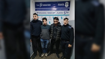 Cuatro personas, dos con uniforme de policía y dos de civil, de pie frente a un cartel azul y blanco de la Comisaría Mar del Plata 5ta