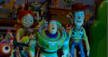 Tres figuras de personajes de dibujos animados, Jessie, Buzz Lightyear y Woody, se encuentran rodeados de juguetes en un estante