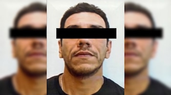 Fotografía frontal de un hombre con cabello corto y camiseta negra, con una franja negra horizontal que cubre sus ojos.
