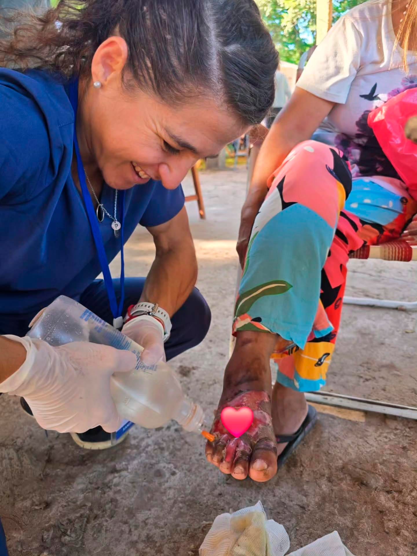 La judoca y médica Paula Pareto, sonriente, ofrece atención médica a una persona como parte de su viaje solidario