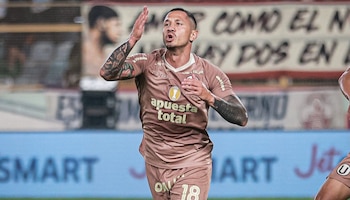 Un futbolista, Gianluca Lapadula, con camiseta marrón y tatuajes en los brazos, celebra un gol con el brazo derecho levantado y la mano izquierda en el pecho