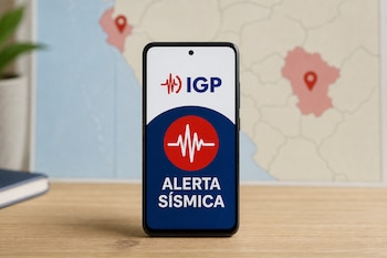 Teléfono móvil en una mesa de madera con una pantalla que dice alerta sísmica y el logotipo del Instituto Geofísico del Perú frente a un mapa.
