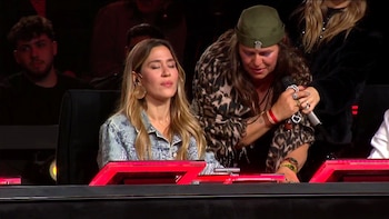 Jimena Barón sentada con los ojos cerrados junto a una persona con prenda estampado de leopardo y gorra que sostiene un micrófono