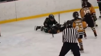 Jugadores de hockey sobre hielo y un árbitro con camiseta a rayas en una pista congelada junto a una valla blanca