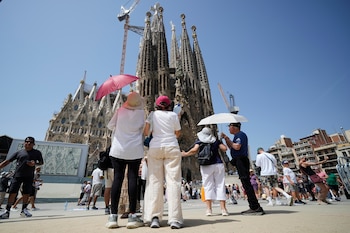Turistas asiáticos con paraguas se resguardan del sol en la Sagrada Familia. (Alejandro García/EFE)