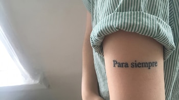 Brazo de persona con tatuaje que dice 'Para siempre' y parte de una camisa de rayas blancas y verdes.