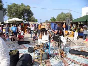 Una pareja de músicos tocan para el mercado en el que de fondo se encuentran puestos.