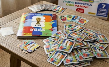 Vista superior del álbum oficial Panini FIFA World Cup 2026 y muchos paquetes de figuritas, algunos abiertos, sobre una mesa de madera