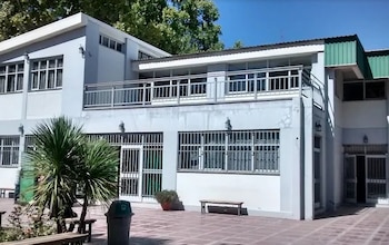 Fachada de un edificio de dos pisos con grandes ventanas, barandilla de metal en la terraza y un patio pavimentado