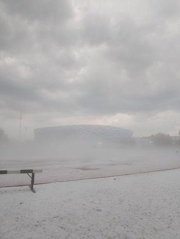 Vista del Estadio Cuauhtémoc parcialmente cubierto por una densa niebla y granizo blanco que cubre el suelo, bajo un cielo nublado gris