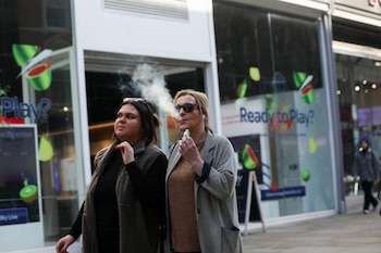 Una mujer sostiene un cigarrillo electrónico mientras vapea en una calle de Manchester, Inglaterra. (Temilade Adelaja / Reuters)