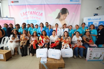 Un grupo de madres con sus bebés y personal de salud posan con cajas de premios frente a una banderola institucional de EsSalud