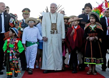 El papa Francisco se da la mano con niños vestidos con trajes tradicionales mientras camina con el presidente boliviano Evo Morales a su llegada al aeropuerto de El Alto, Bolivia, el miércoles 8 de julio de 2015. (AP Photo/Gregorio Borgia)