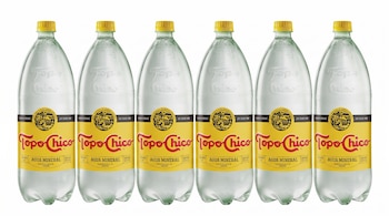 Seis botellas de plástico de agua mineral Topo Chico con tapas amarillas y etiquetas amarillas que dicen "Agua Mineral Embotellada de Origen".