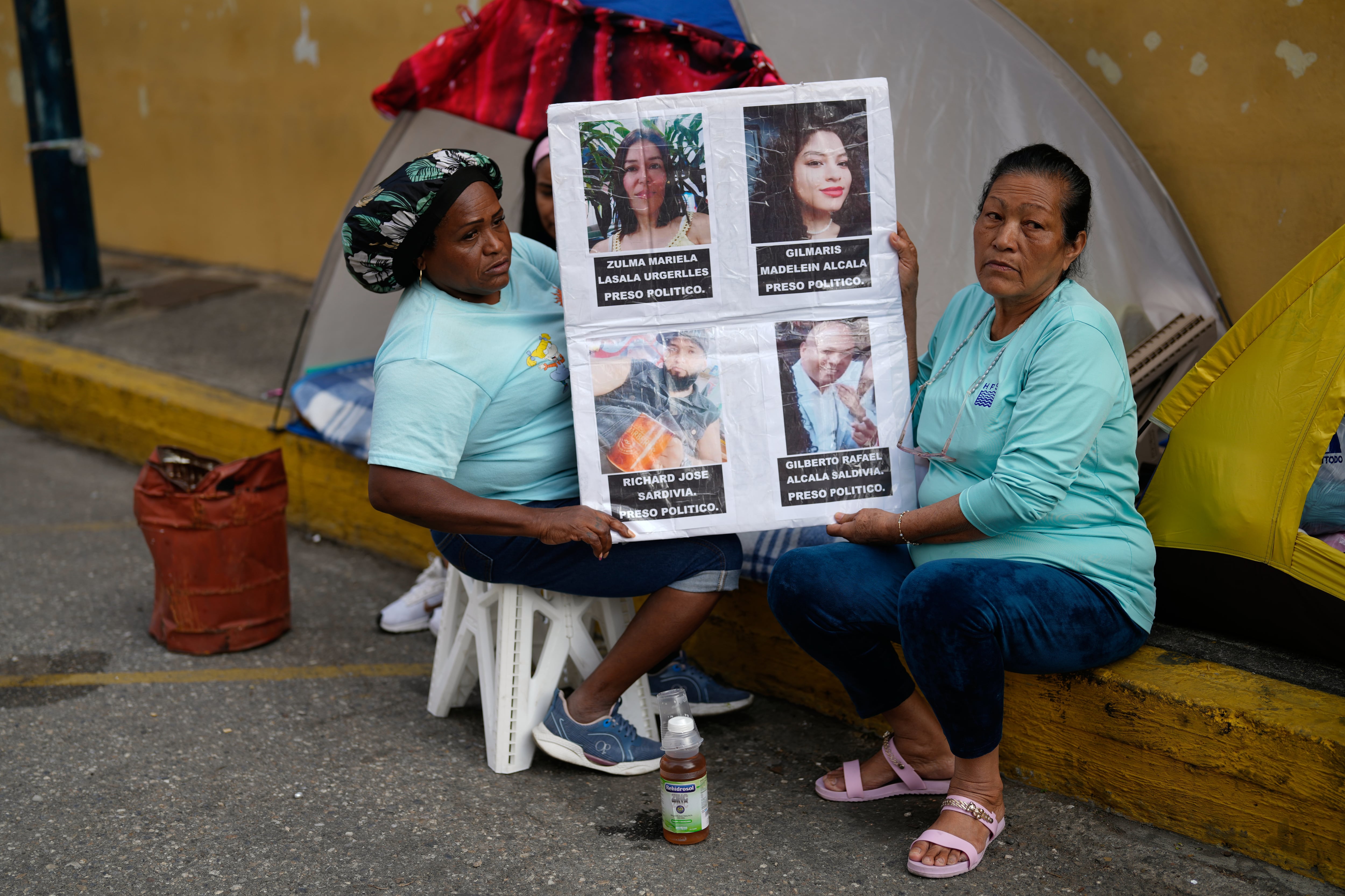 Marina Saldivia (derecha) sostiene fotos de sus hijos, Gilberto Alcalá y Richard Saldivia (abajo), quienes, según ella, fueron detenidos hace dos meses y no han tenido noticias de ellos desde entonces, afuera de la Zona 7 de la estación de la Policía Nacional Bolivariana en Caracas, Venezuela, el lunes 19 de enero de 2026 (Foto AP/Ariana Cubillos)