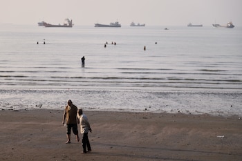 Bañistas en la costa de Bandar Abbas, Irán, con buques de carga anclados en el estrecho de Ormuz al fondo, el 1 de junio de 2026. El paso estratégico, por donde transita cerca del 20% del suministro mundial de petróleo, es uno de los principales puntos de tensión en la guerra entre EE.UU. e Irán. (Amirhosein Khorgooi/ISNA/AP)