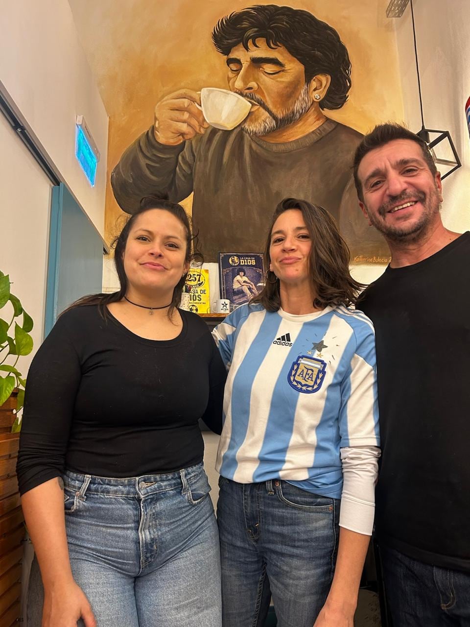 Diego Arvilly y Laura Villanueva posan junto a la actriz Laura Azcurra en el local maradoniano, ubicado en La Paternal (Donato Álvarez al 2000) (@astroscafe_)