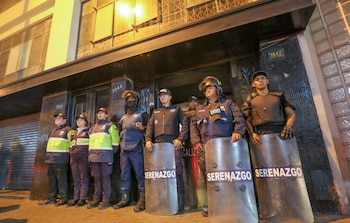 Agentes uniformados de Serenazgo y Policía Nacional con escudos "SERENAZGO" de pie frente a un edificio con las entradas 1044 y 1042 durante un operativo nocturno