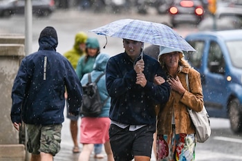 Varias personas se protegen de la lluvia en Palma. (Miquel A. Borràs/EFE)