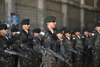 Fila de soldados con uniformes camuflados, boinas verdes, lentes de sol, chalecos tácticos y fusiles de asalto