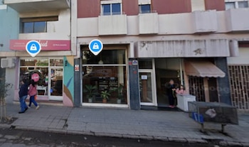 Vista de locales comerciales en la planta baja de un edificio con vereda de baldosas y dos iconos de ubicación