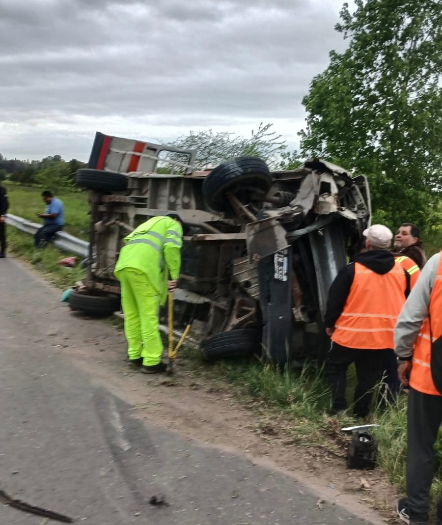 Personal con chalecos de seguridad inspecciona la estructura de un vehículo volcado a un costado de la carretera.