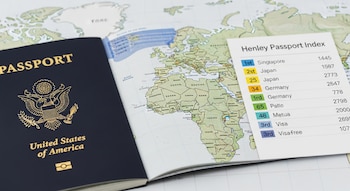 Primer plano de un pasaporte de EE. UU. abierto sobre un mapa mundial, con países resaltados y una lista del Índice de Pasaportes Henley visible.