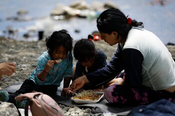 Una migrante ecuatoriana come junto a sus hijas en la selva mientras esperan para ser trasladados en canoa desde la Quebrada León hasta a la comunidad de Bajo Chiquito en Darién (Panamá), en una fotografía de archivo. (EFE/ Bienvenido Velasco)